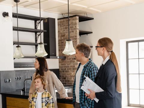 An agent showing a family around the kitchen of an empty house